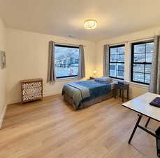 Bedroom with light wood-style flooring, a textured ceiling, and multiple windows