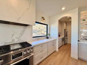 Kitchen with stainless steel appliances, light wood finished floors, recessed lighting, light stone countertops, and white cabinets