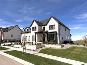 View of the front of the home featuring stone siding, a front lawn, four fruit trees, and a covered porch
