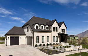French country style house with a mountain view, a shingled roof, driveway, an attached garage, and brick siding