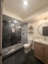 Full bath featuring vanity, a shower stall, and dark tile patterned flooring