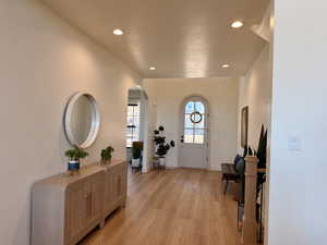 Entrance foyer featuring arched walkways, light wood-style floors, and recessed lighting