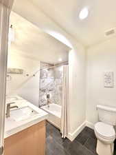 Full bathroom featuring double vanity, shower / bath combo, and dark tile patterned floors
