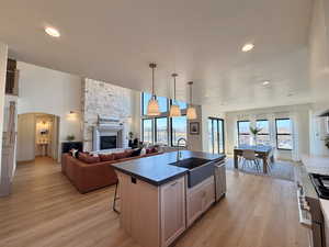 Kitchen with open floor plan, a kitchen island with a Farm sink, Signature Kitchen Suite Appliances, a fireplace, and dark countertops