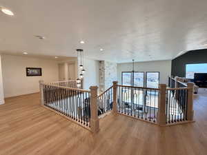 Hallway with an upstairs landing, light wood finished floors, a textured ceiling, and plenty of natural light