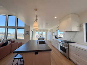 Kitchen with stainless steel gas range oven, an island with sink, tasteful backsplash, light wood finished floors, and open floor plan