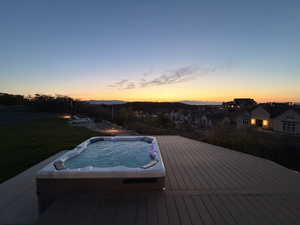 Pool at dusk with a wooden deck, a residential view, and a yard