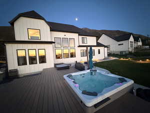 Wooden deck with an outdoor hot tub and a yard