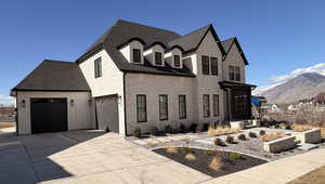View of front of house featuring driveway, a mountain view, and roof with shingles