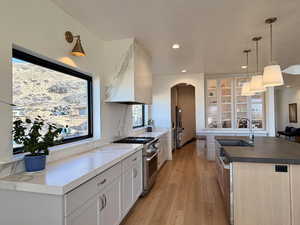 Kitchen featuring arched walkways, premium appliances, dark countertops, decorative light fixtures, and a center island with sink