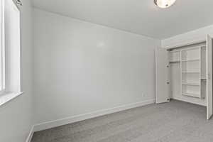 Unfurnished bedroom with light carpet and a closet