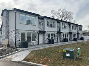 View of front of house with stone siding, stucco siding, and a front yard