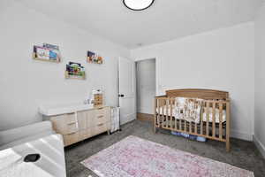 Bedroom featuring dark colored carpet and a nursery area