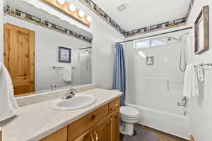 Full bath with vanity, shower / tub combo with curtain, and dark wood finished floors