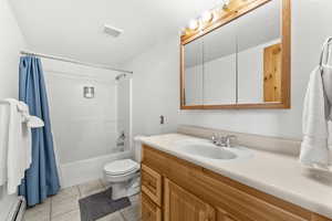 Full bathroom with shower / tub combo, vanity, a baseboard heating unit, and light tile patterned flooring