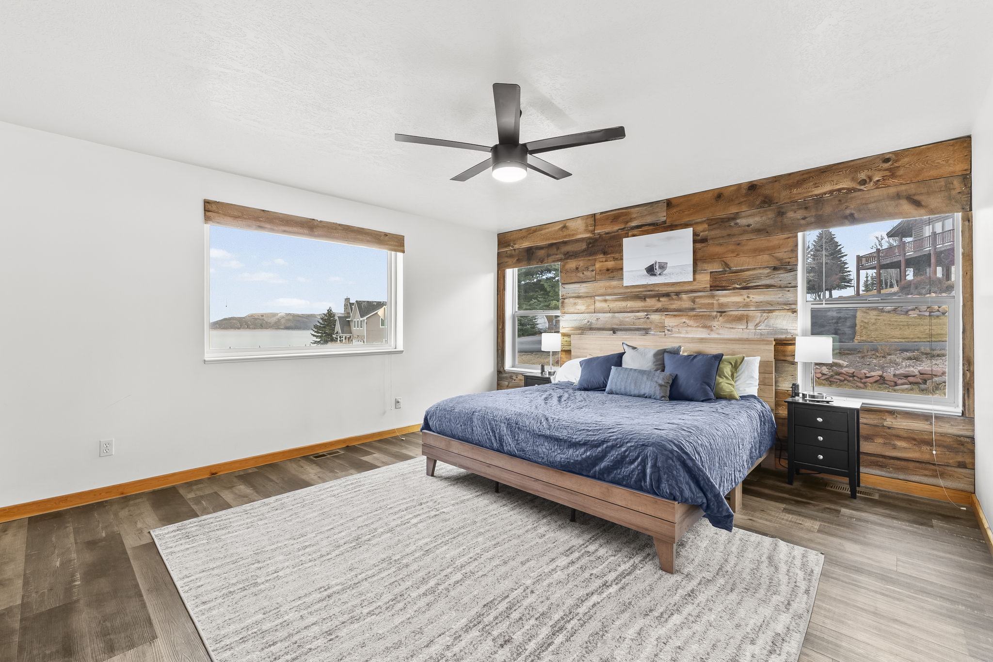 Bedroom with wooden walls, a ceiling fan, and wood finished floors