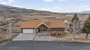 View of front of home featuring stone siding, a mountain view, a metal roof, driveway, and an attached garage