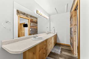 Full bath with double vanity and dark wood-style floors