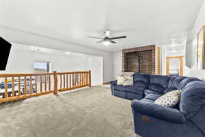 Living area featuring carpet, a wood stove, and ceiling fan
