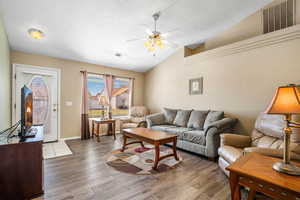 Living room has vaulted ceilings, plant shelves, and ceiling fans