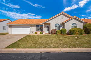 Mediterranean / spanish house featuring stucco siding, an attached garage, a front yard, driveway, and a tile roof