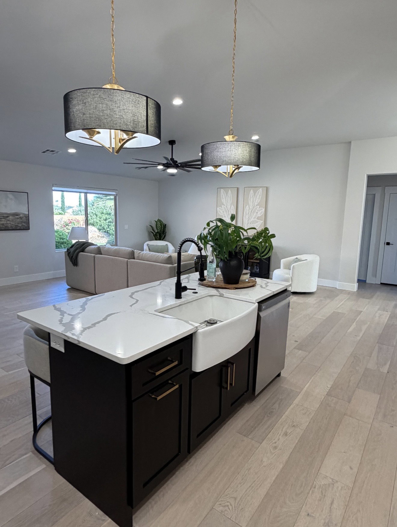 Kitchen island with a farmhouse sink, quartz countertop, and dark cabinetry