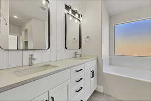 Bathroom featuring a bath, double vanity, and light tile patterned floors