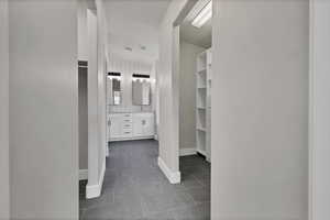 Bathroom with double vanity, a walk in closet, and dark tile patterned floors
