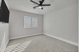 Empty room featuring light colored carpet and ceiling fan