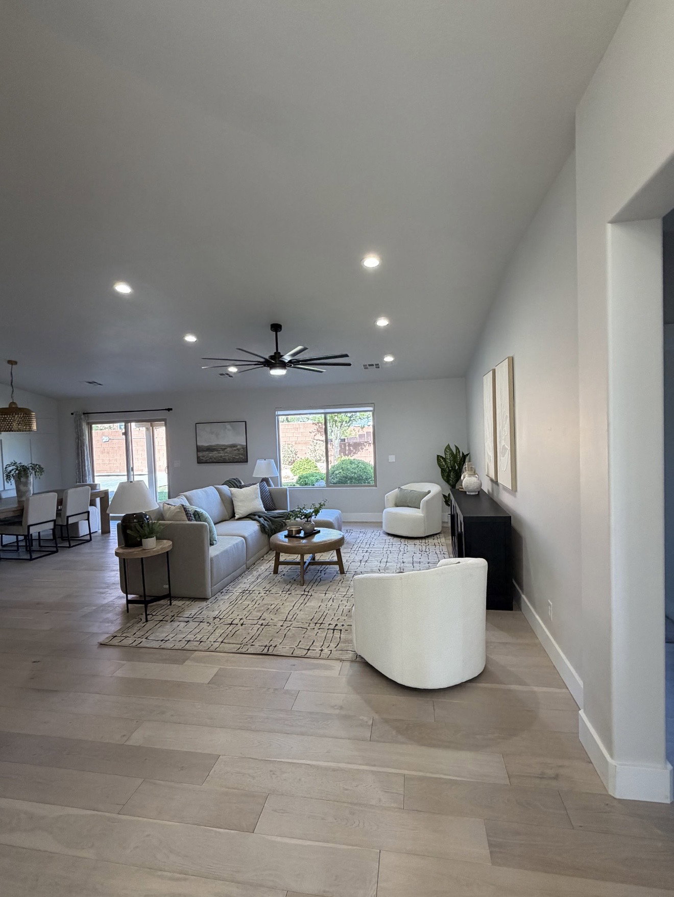 Open-concept living space with light wood-finish flooring, recessed lighting, a contemporary ceiling fan, and large windows providing natural light