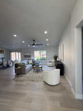 Open-concept living space with light wood-finish flooring, recessed lighting, a contemporary ceiling fan, and large windows providing natural light