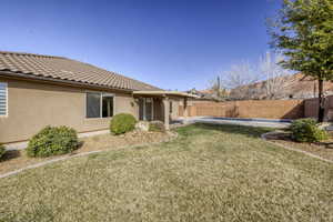 Back of house with stucco siding, a fenced backyard, and a tiled roof