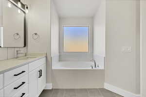 Full bathroom with a garden tub, vanity, and light tile patterned floors
