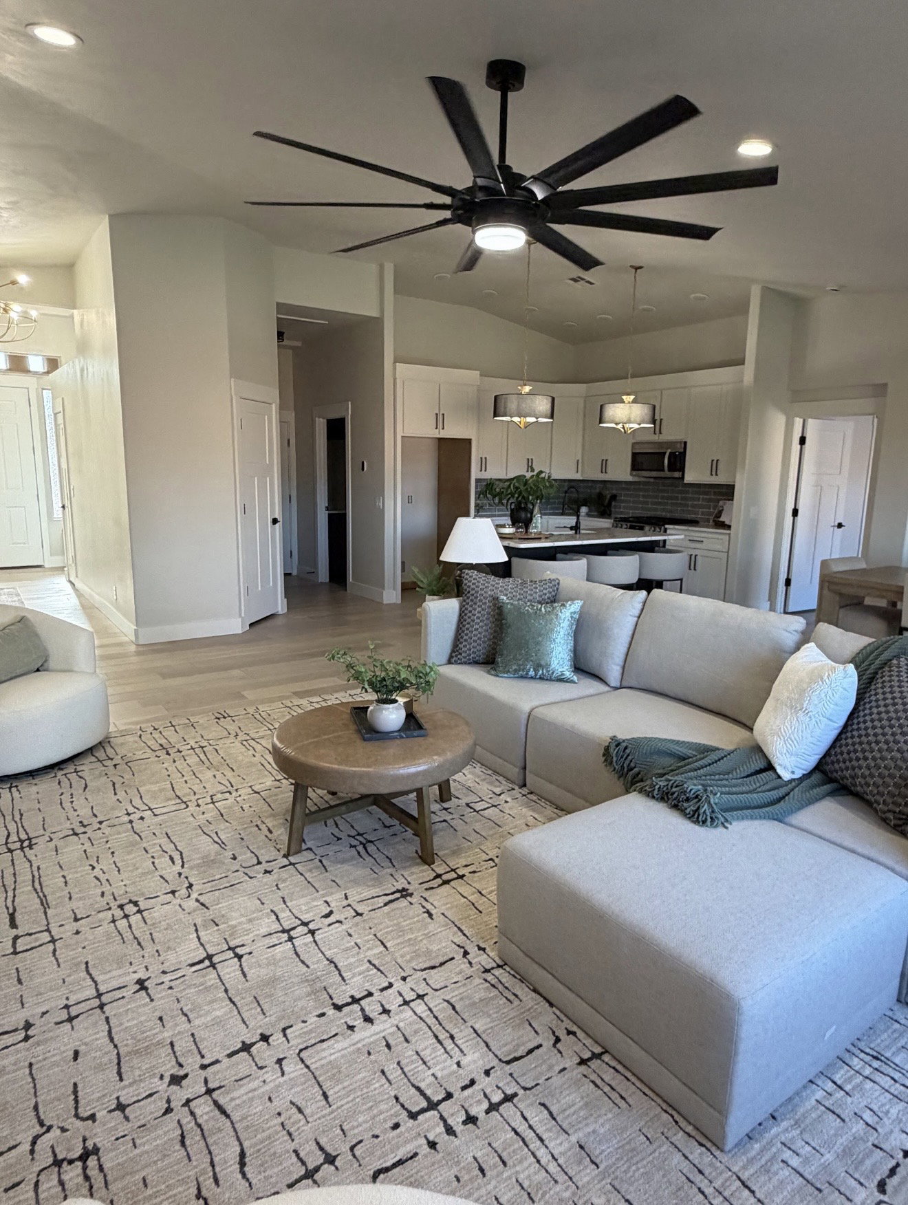Open-concept living space featuring vaulted ceilings, a large ceiling fan with integrated lighting, wood-finish flooring, and recessed lighting