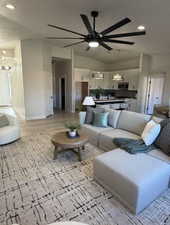 Open-concept living space featuring vaulted ceilings, a large ceiling fan with integrated lighting, wood-finish flooring, and recessed lighting
