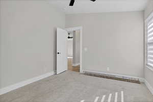 Unfurnished room with light carpet, a baseboard heating unit, and ceiling fan