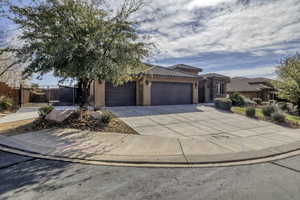 View of front facade with an attached garage, stucco siding, concrete driveway, a tiled roof, and a gate