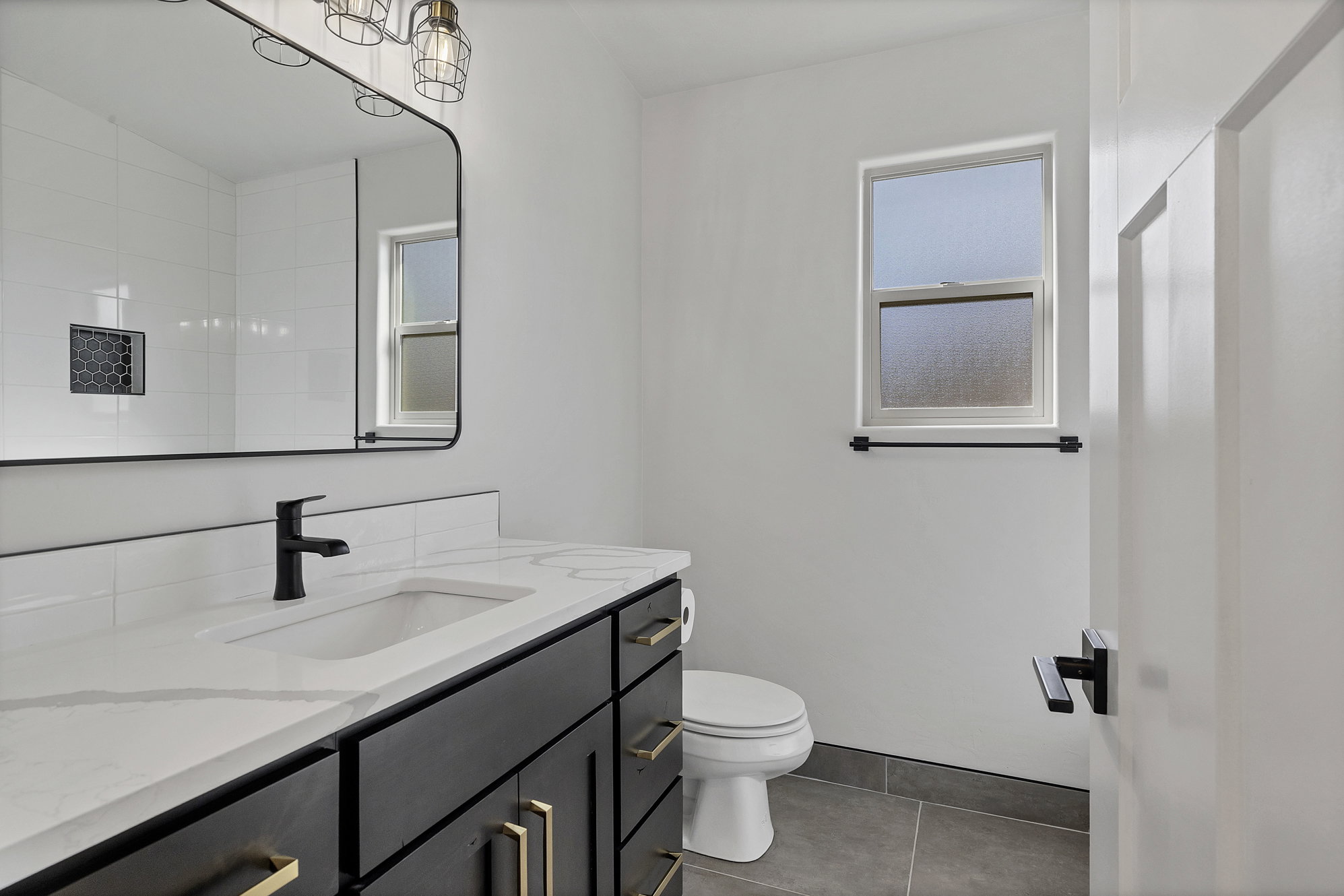 Bathroom featuring vanity, dark tile patterned flooring, and plenty of natural light