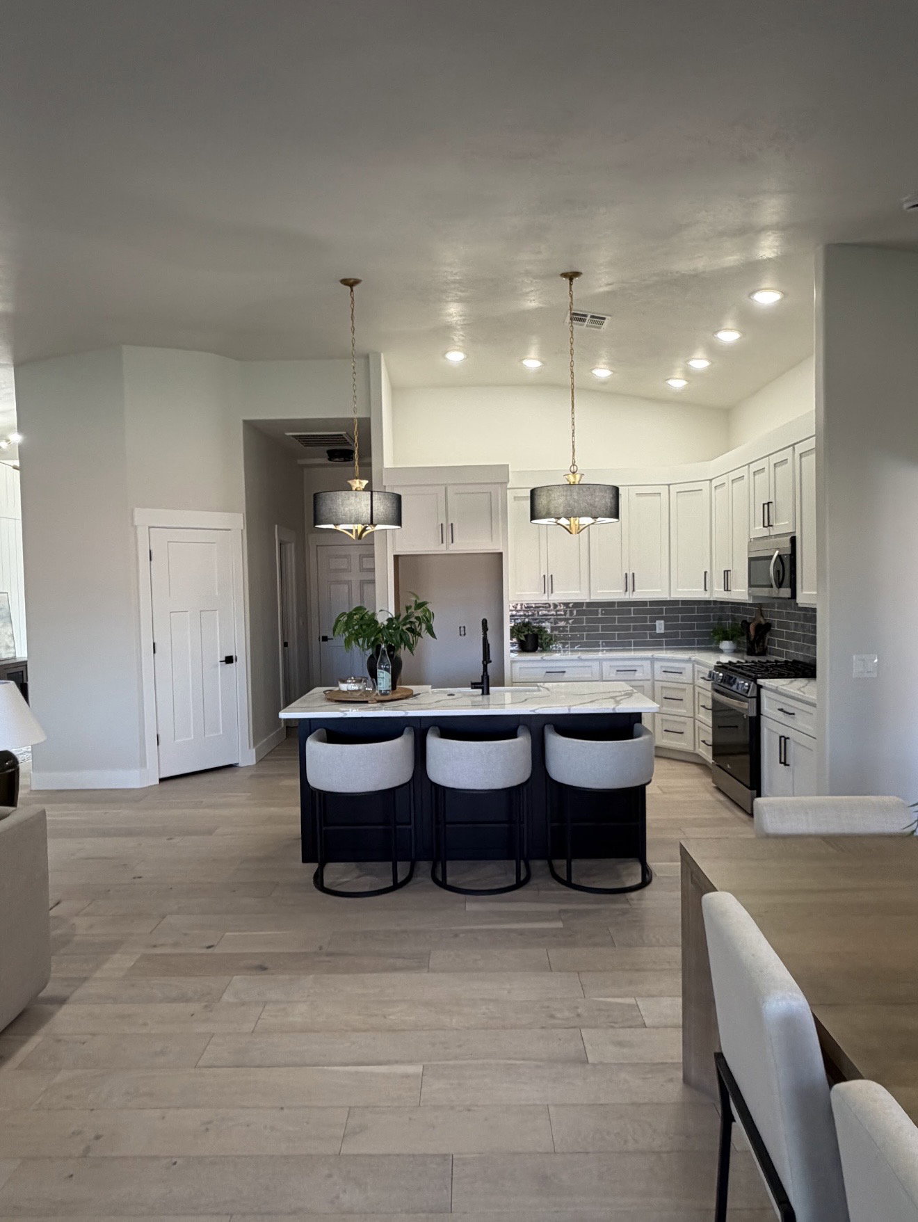 Gourmet kitchen featuring a central island with countertop seating, light wood-finish flooring, white cabinetry, a subway tile backsplash, and recessed lighting