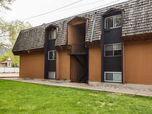 Rear view of house featuring mansard roof and a lawn