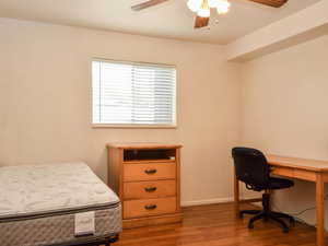 Bedroom with wood finished floors, a ceiling fan, and a desk