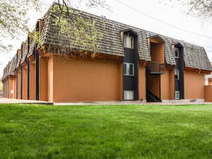 Back of house with mansard roof and a lawn