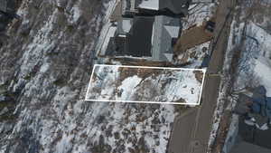Snowy aerial view featuring property parcel outlined and a residential view