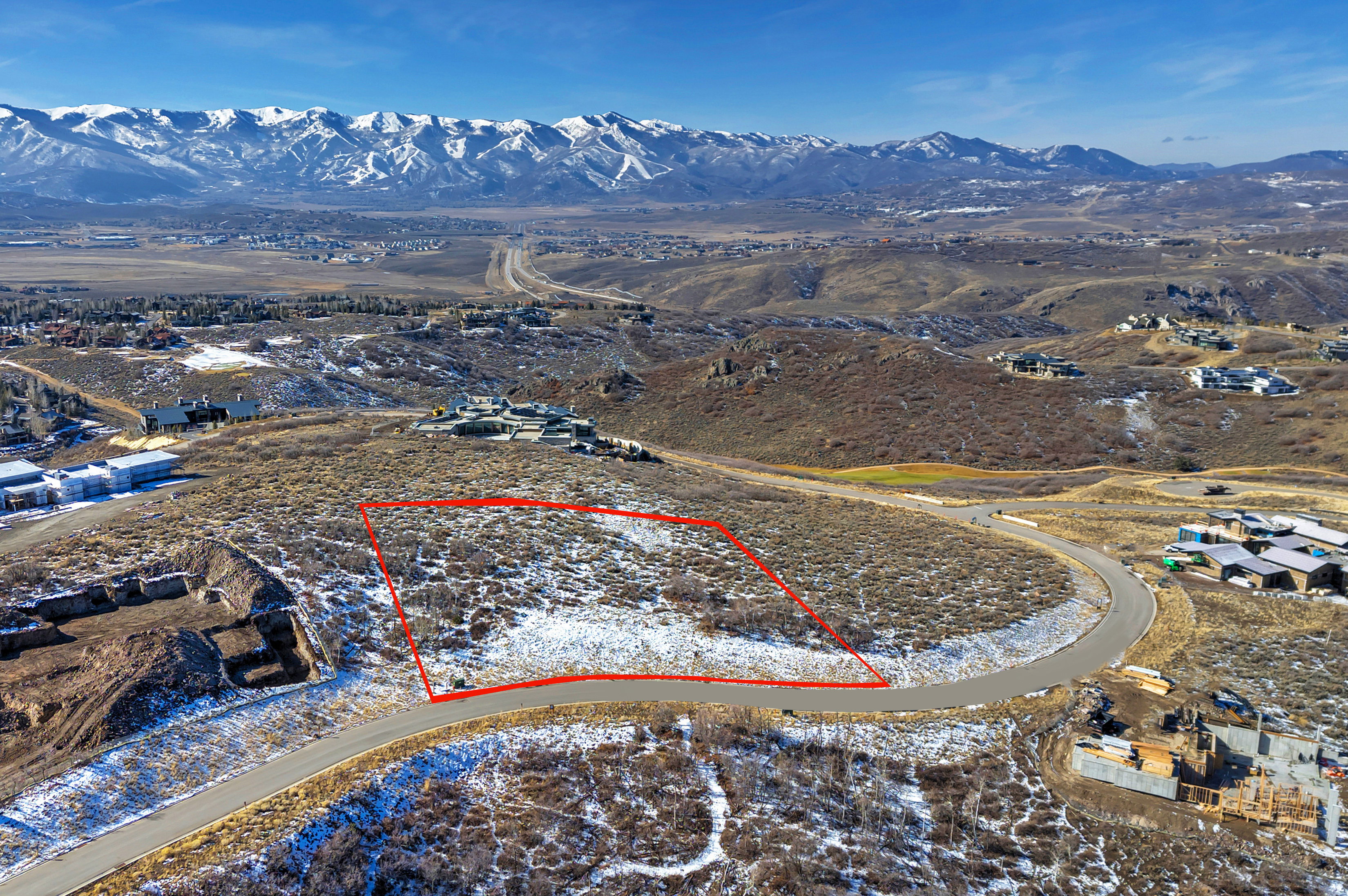 Aerial view of property and surrounding area with property parcel outlined and a mountainous background