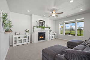 Living room featuring recessed lighting, carpet, ceiling fan, fireplace, and a textured ceiling