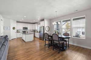Dining area featuring wood finished floors, hanging lights, and a textured ceiling