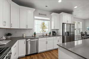 Kitchen with stainless steel appliances, wood finished floors, white cabinetry, recessed lighting, and tasteful backsplash