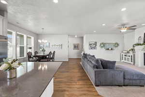 Living area featuring wood-style floors, ceiling fan, suspended lighting, and a textured ceiling
