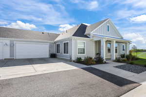View of front facade featuring a shingled roof, concrete driveway, a garage, and board and batten siding
