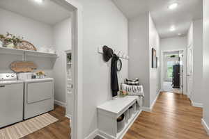 Laundry room with wood-style floors, a textured ceiling, separate washer and dryer, and recessed lighting